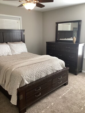 A bedroom with a bed, dresser, and ceiling fan.