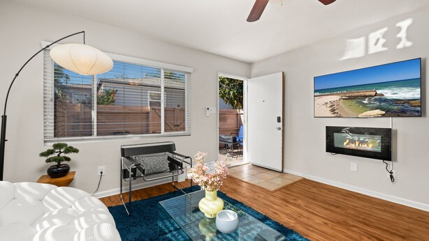 A living room with a sofa, a coffee table with a vase, a TV, and a fireplace. - Cozy Pacific Beach 2BR Patio Fire Pit (San Diego)