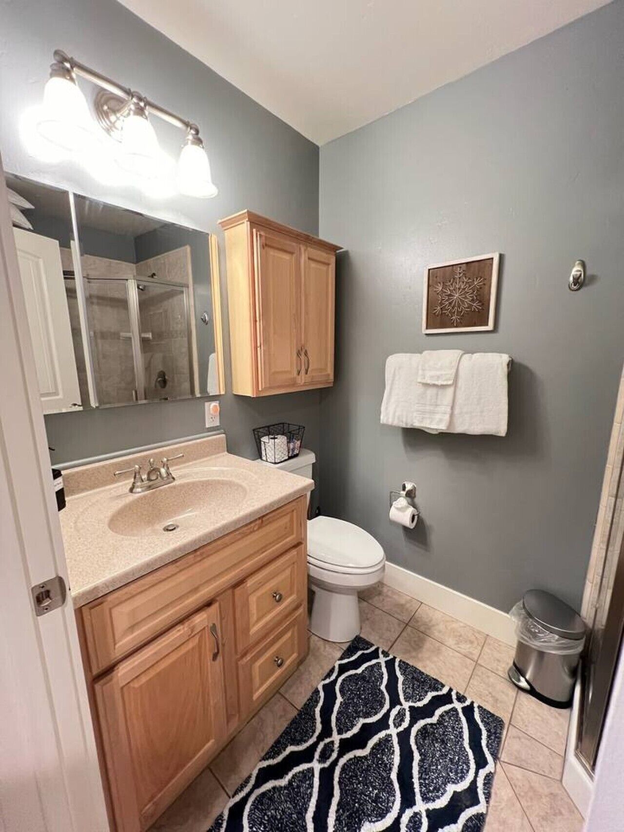 A bathroom with a vanity, sink, mirror, toilet, and a shower area.
