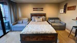 A bedroom with a bed, two sofas, a small table, and a window with curtains. - Ski-in, Chill-out Tahoe Donner Condo (Truckee)