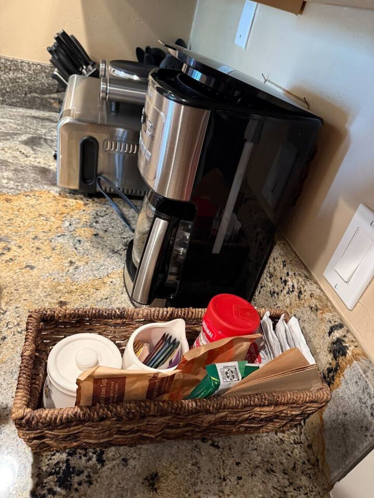 Eine Küche mit Kaffeemaschine, Toaster und einer Korb, der eine Tasse Kaffee, Besteck und eine Zuckerpackung enthält.