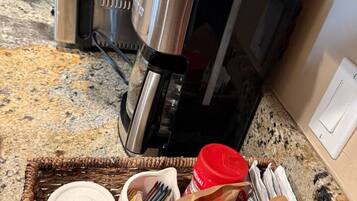 Eine Küche mit Kaffeemaschine, Toaster und einer Korb, der eine Tasse Kaffee, Besteck und eine Zuckerpackung enthält.