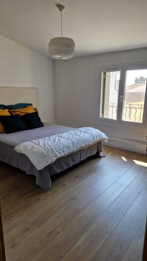 A bedroom with a bed, a hanging light fixture, a window, and a view of the outside. - Charming village house in Provence with courtyard (CHATEAUNEUF DE GADAGNE)