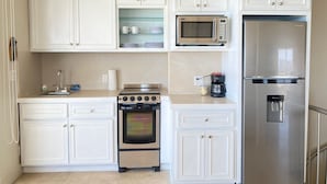 Une cuisine avec des armoires blanches, une cuisinière en acier inoxydable, un four à micro-ondes et un réfrigérateur.