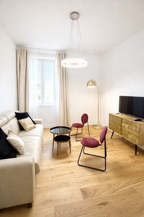 A modern living room with a sofa, two chairs, a small table, a floor lamp, a TV, and a cabinet. - Cozy apartment in the Vatican district (Roma)