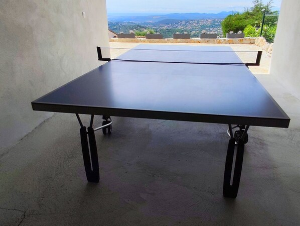 A ping pong table in an outdoor area with a view of a cityscape.