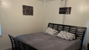 Une chambre à coucher avec un lit, deux oreillers, une tête de lit, une œuvre d’art murale et une fenêtre.