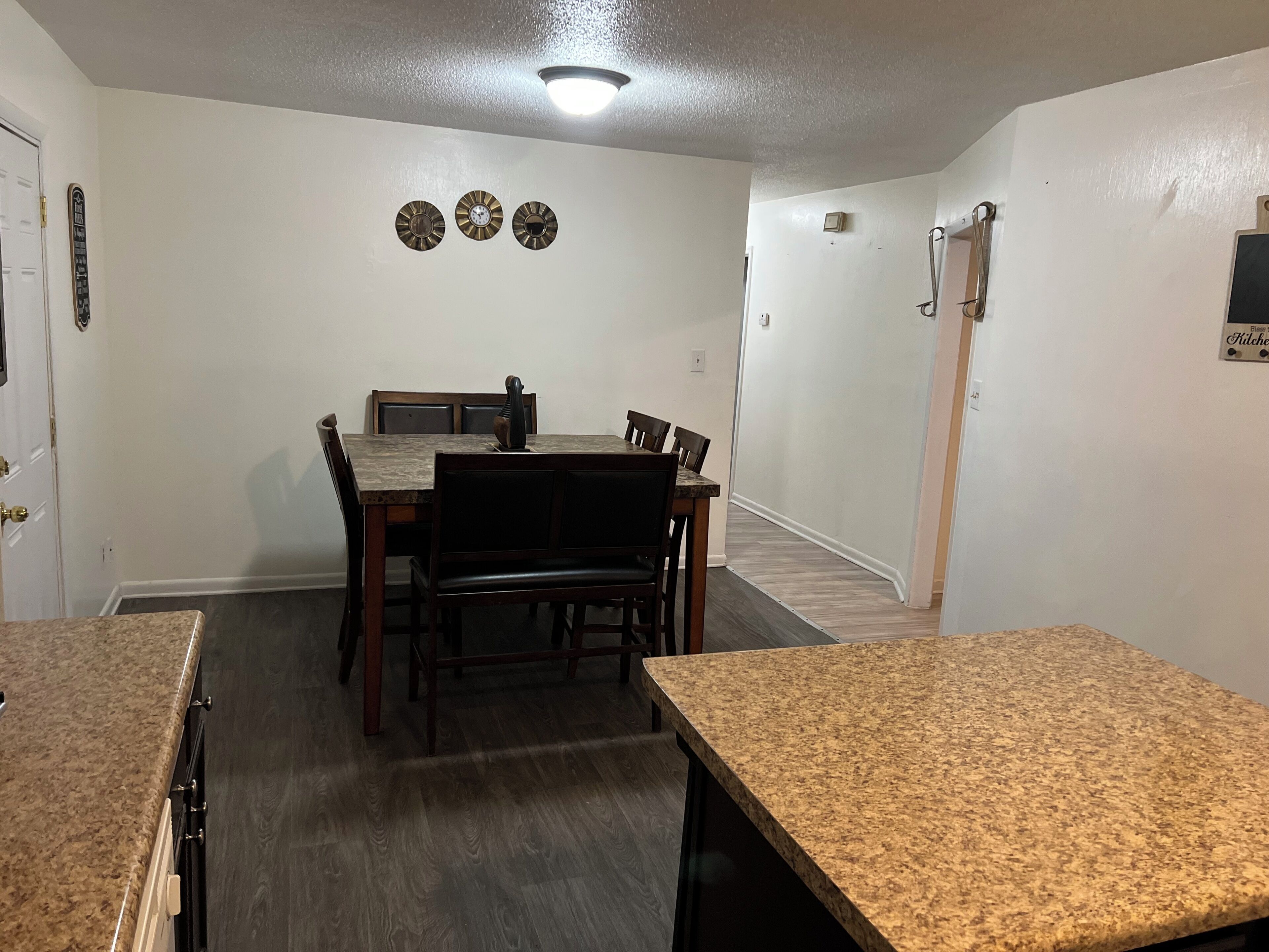 A dining area with a table and chairs, a clock on the wall, and a door with a sign.