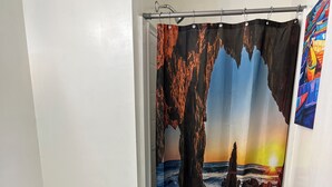 Une salle de bain équipée de toilettes, d’un lavabo et d’un rideau de douche représentant un paysage rocheux au coucher du soleil.
