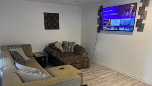 Un salon comprenant un canapé d’angle, une petite table et un téléviseur à écran plat fixé au mur.