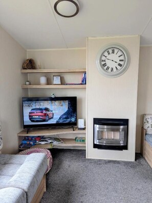 Ein Wohnzimmer mit Flachbildfernseher, Kamin und Wanduhr.