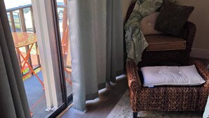 A room with a wicker sofa, a patterned rug, and a view through a glass door. - Hibiscus House - Relaxing Tropical Getaway with Pool (Fort Myers)