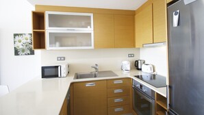 Eine moderne Küche mit Holzausstattung, einem Edelstahlkühlschrank, einer Mikrowelle, einer Spüle und einem Toaster.