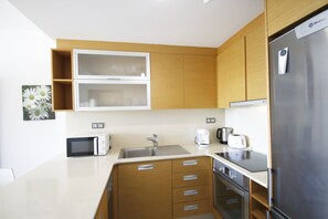 A modern kitchen with wooden cabinets, a stainless steel refrigerator, a microwave, a sink, and a toaster. - Apartment Panoramic 23 by Parc Mont-roig (Miami Playa)
