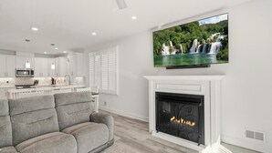 Een moderne woonkamer met een open haard, een flatscreen televisie en een bank.