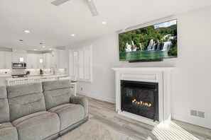 Ein modernes Wohnzimmer mit Kamin, Flachbildfernseher und einer Couch.