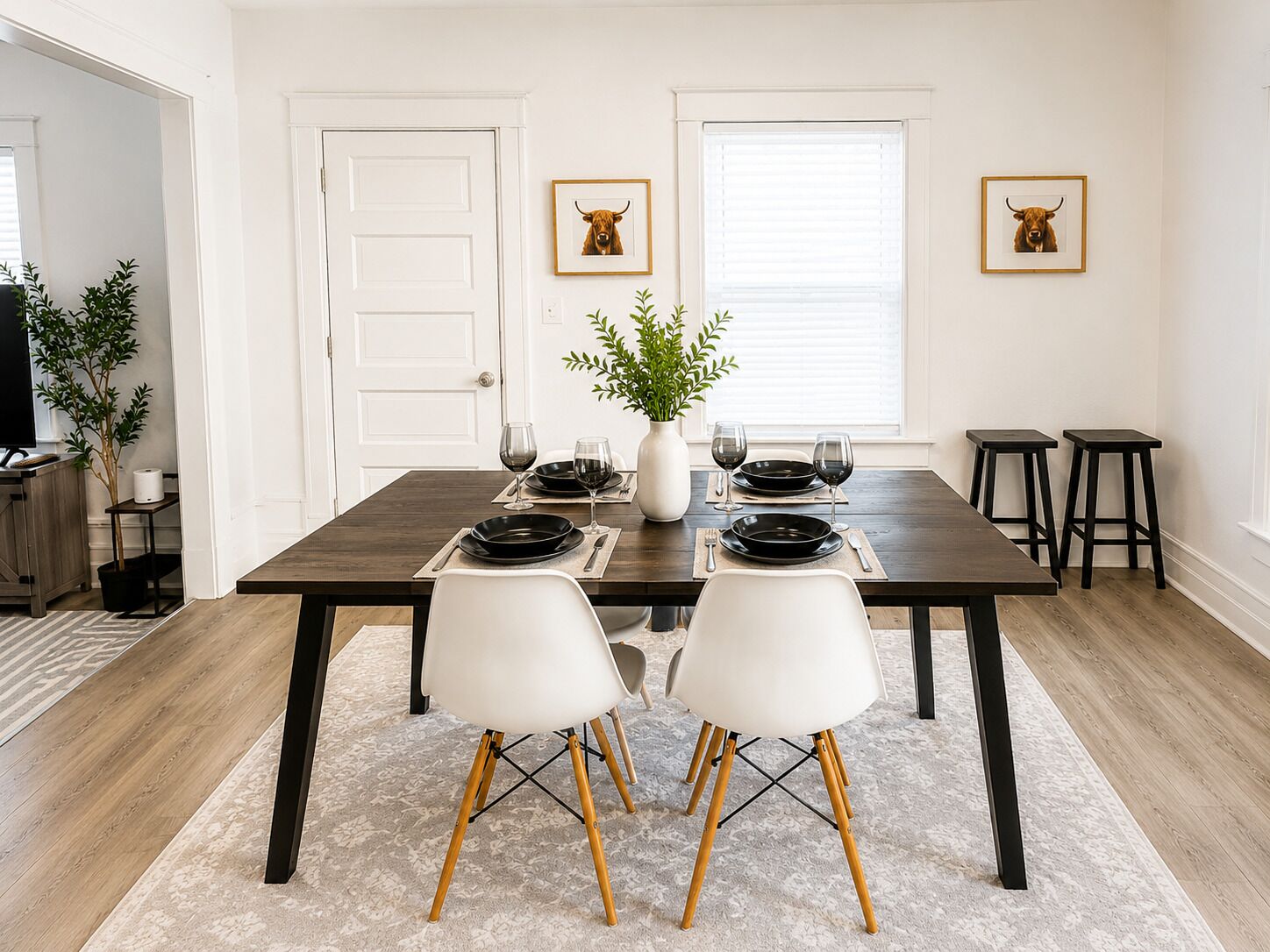 A dining area with a dark wooden table, white chairs, and a vase with green plants.. 2-bedroom building in fabulous Niagara Falls with AC