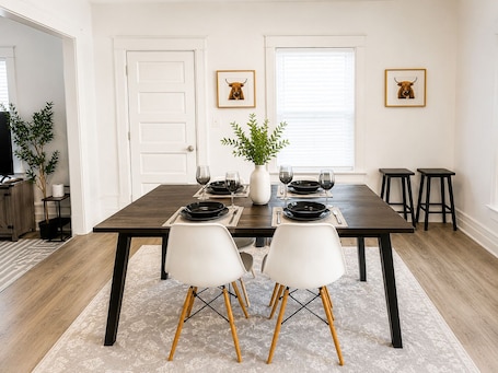 A dining area with a dark wooden table, white chairs, and a vase with green plants.. 2-bedroom building in fabulous Niagara Falls with AC