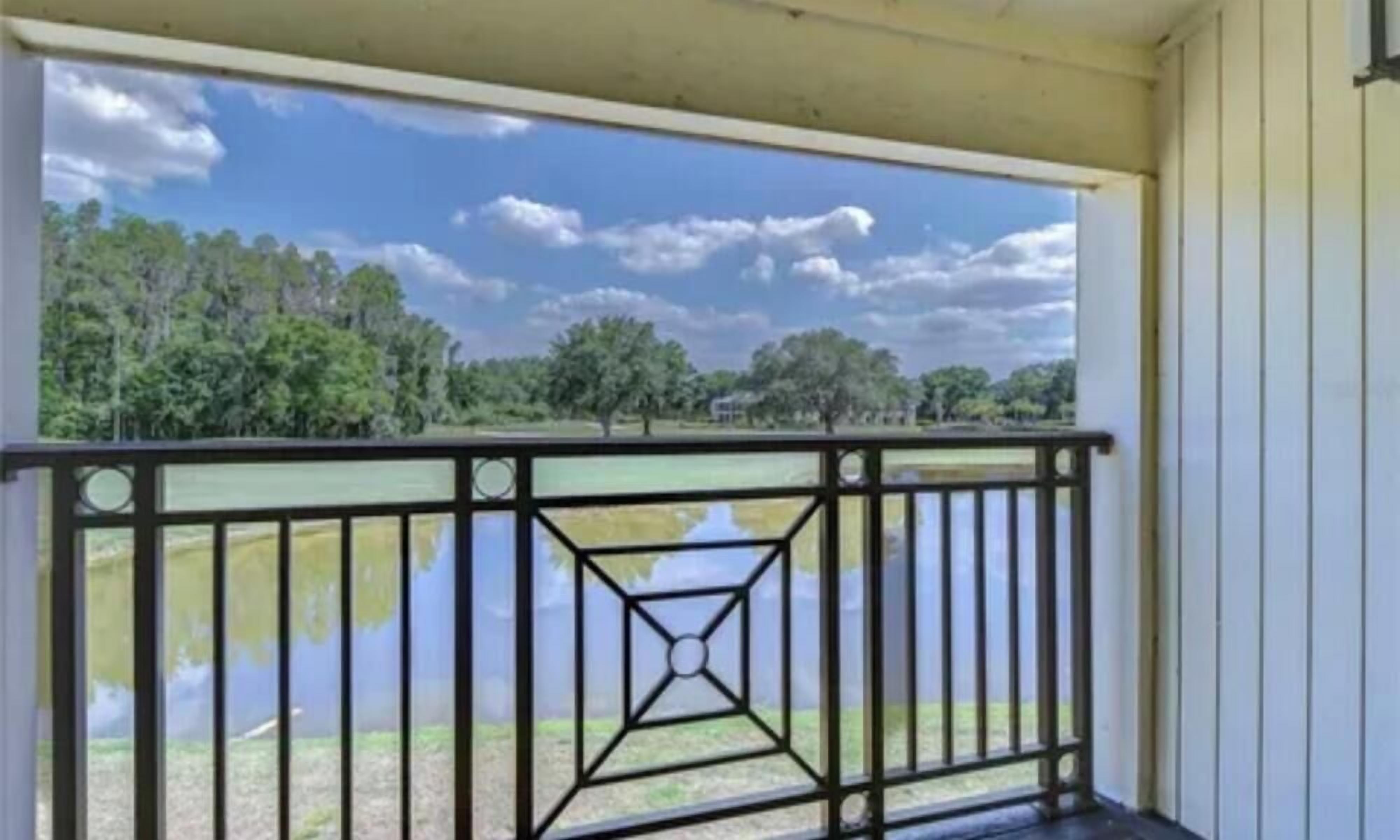 A balcony with a metal railing overlooking a body of water and trees.