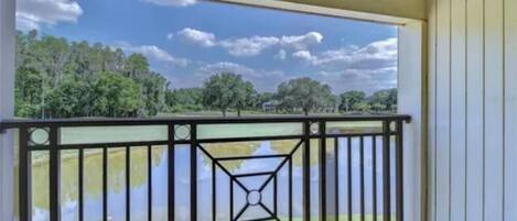 A balcony with a metal railing overlooking a body of water and trees.