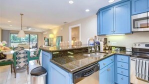 Una cocina moderna con armarios azules, encimera de granito y lavavajillas.