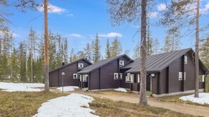 A cabin with a dark exterior, a covered porch, and a snow-covered path leading to it.
