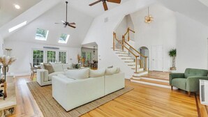 Ein geräumiges Loft mit hohen Decken, Dachfenstern, einer Treppe und einem großen weißen Sofa.