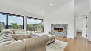A modern living room with a fireplace, large windows, and a sofa. - Contemporary Shinnecock Hills Estate: Saltwater Heated Pool, Perfect Escape... (Southampton)