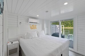 A bedroom with a bed, a nightstand, an air conditioning unit, and a sliding glass door to a balcony. - Tequila Sunrise - Relaxing Getaway Lake Cumberland (Russell Springs)