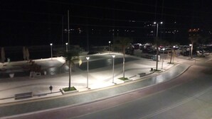 Een nachtelijke straat met straatverlichting, geparkeerde auto's en een gebogen weg.