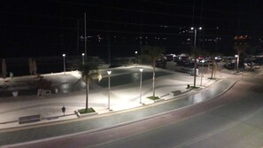 Ein belebter Straßenabschnitt bei Nacht mit Straßenlaternen, parkenden Autos und einer gewundenen Straße.