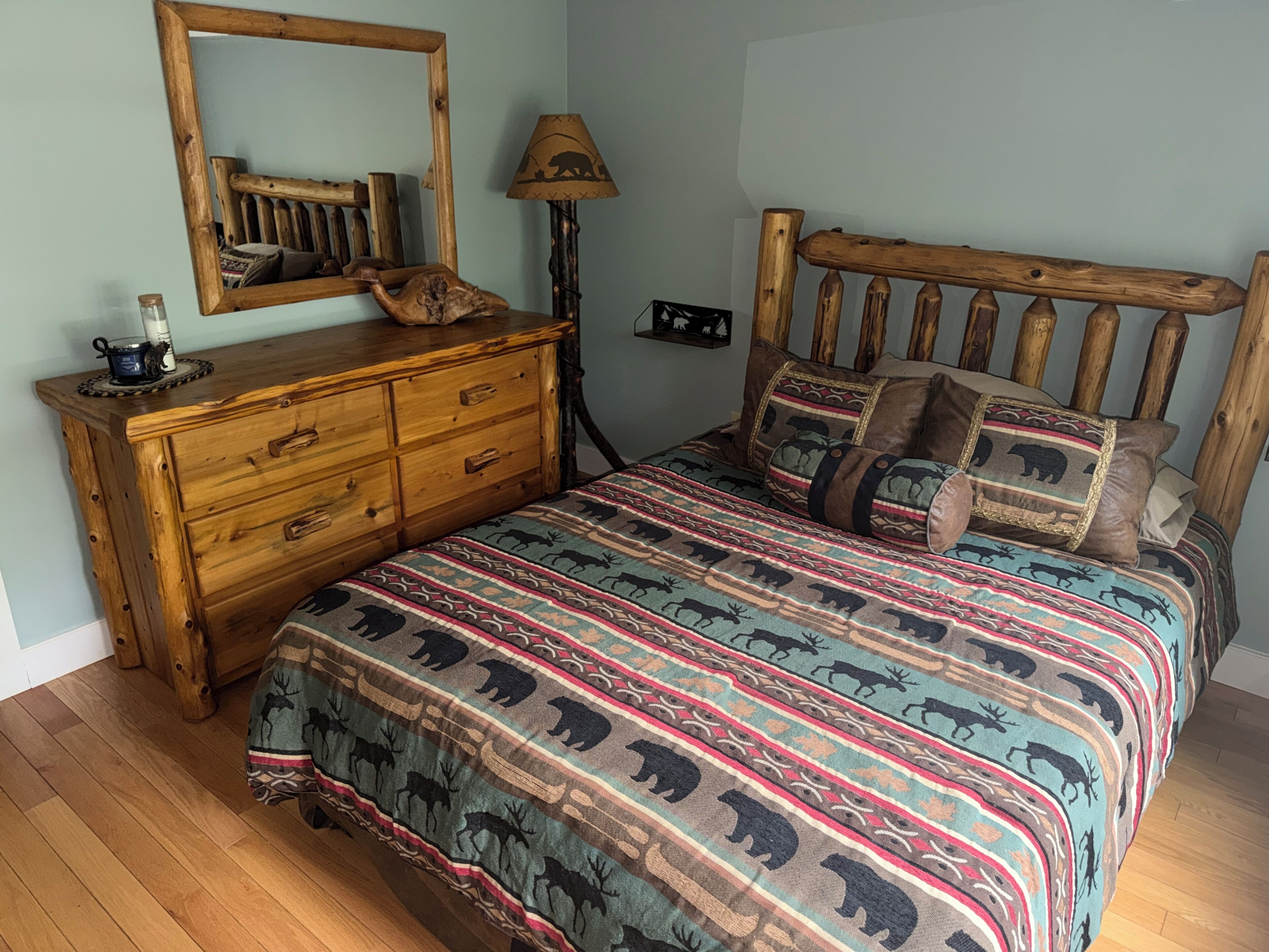 Una camera da letto con un letto con struttura in legno, una cassettiera, uno specchio e una lampada.