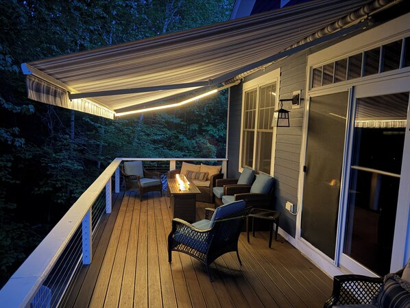 Une terrasse en bois, dotée de mobilier d’extérieur, d’une pergola et offrant une vue sur la forêt environnante.
