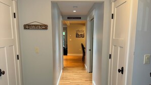 A hallway with wooden flooring, white walls, and a sign that reads 'Life is better at the lake.' - Welcome to the Bear’s Den. A Delightful house on Lake Winnipesaukee in Meredith. (Meredith)