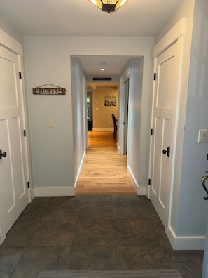 A hallway with wooden flooring, white walls, and a sign that reads 'Life is better at the lake.'