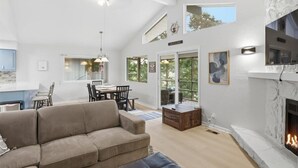 A spacious living area with a fireplace, a dining area, and a kitchen visible through an open door.