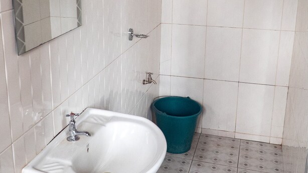 Une salle de bain avec un lavabo blanc, un miroir, une douche et un tapis de bain bleu.
