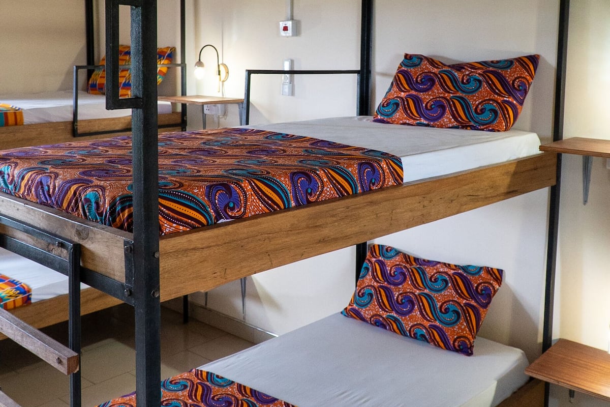 A bunk bed room with a wooden frame, white walls, and patterned bedding.