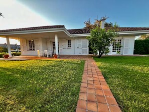 A house with a covered porch, a brick pathway, and a well-maintained lawn.