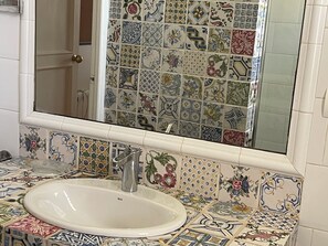 A bathroom with a white sink, a mirror, and a tiled backsplash with various patterns.