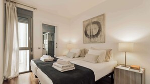 Ein Hotelzimmer mit Bett, Nachttischlampen, einem Gemälde und Blick ins Freie.