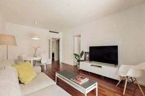 Een moderne woonkamer met een bank, salontafel, televisie en een eethoek.