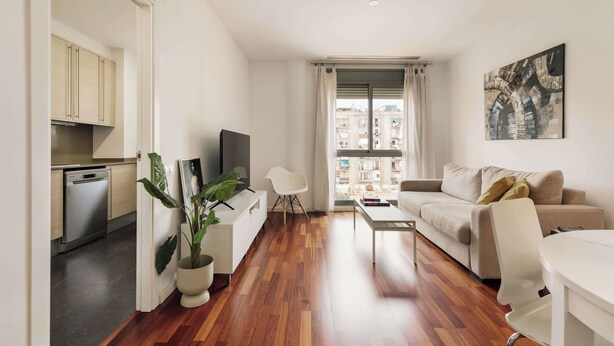 Eine moderne Wohnung mit Küche, einem Wohnbereich inklusive Sofa und Couchtisch sowie einem Essbereich mit Tisch und Stühlen.