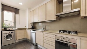 Une cuisine moderne dotée d’appareils électroménagers en acier inoxydable, de meubles en bois et d’un four encastré.