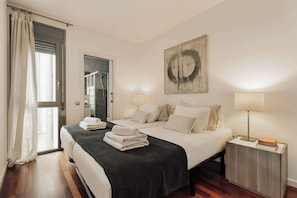 Een hotelkamer met een bed, nachtlampjes, een schilderij en uitzicht op buiten.