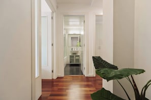 Een gang met houten vloeren die leidt naar een badkamer en een keuken.