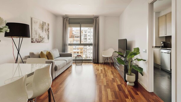 Un appartement moderne comprenant un coin repas, un canapé, une télévision, une cuisine et de grandes fenêtres.