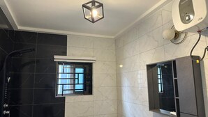 Un baño moderno con ducha, ventana, espejo y lámpara en el techo.