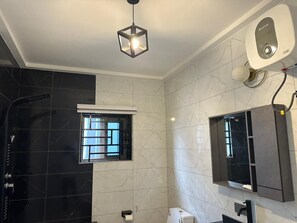 Un baño moderno con ducha, secamanos, ventana y espejo.