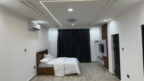 Un dormitorio moderno con cama, televisor de pantalla plana y lámpara en el techo.
